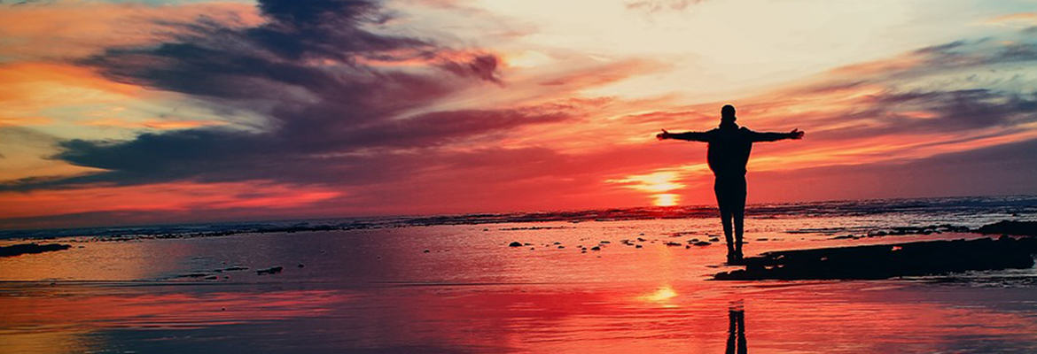 Man standing on shore at sunset